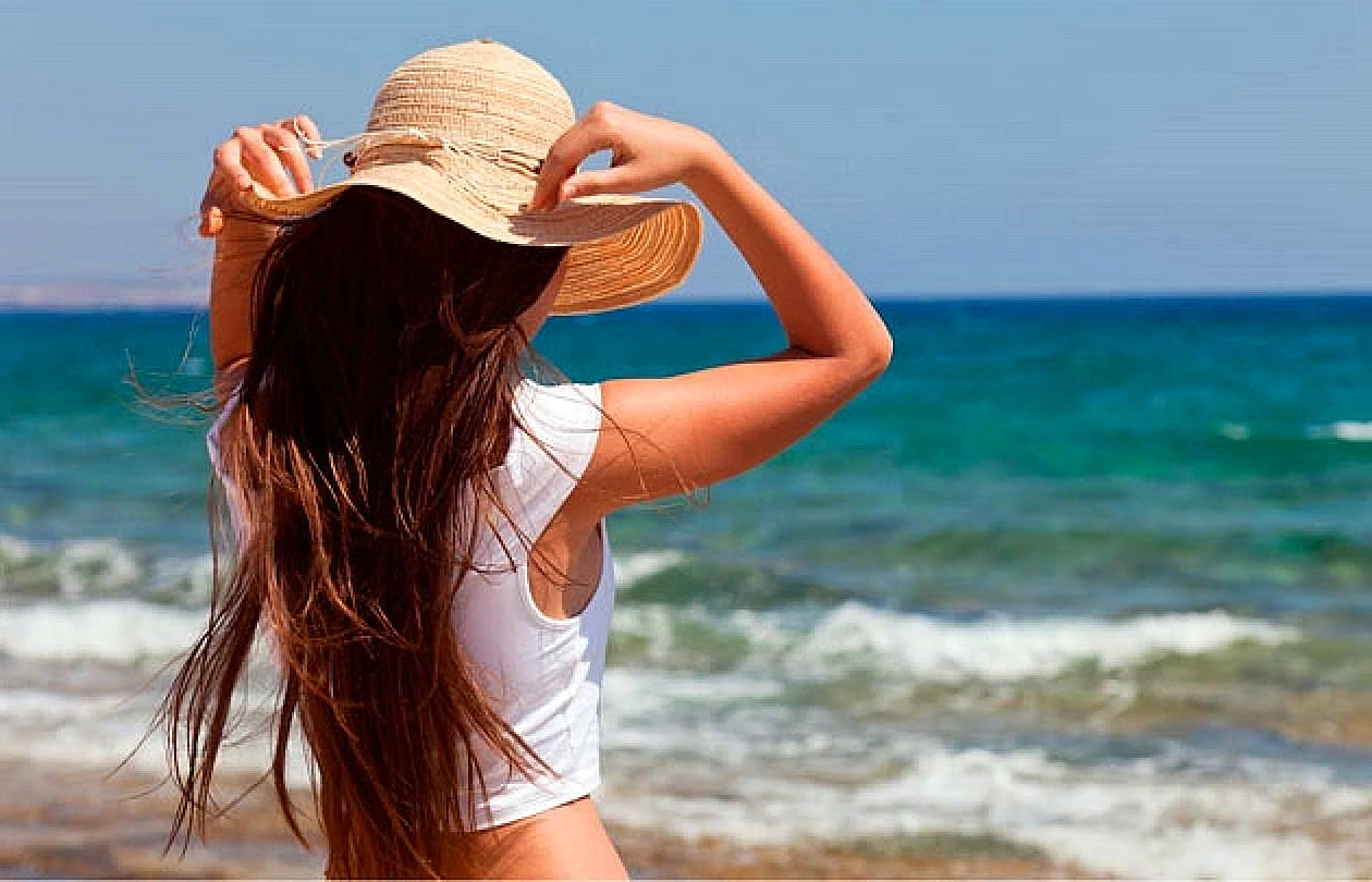 Девушка в шляпе на пляже со спины