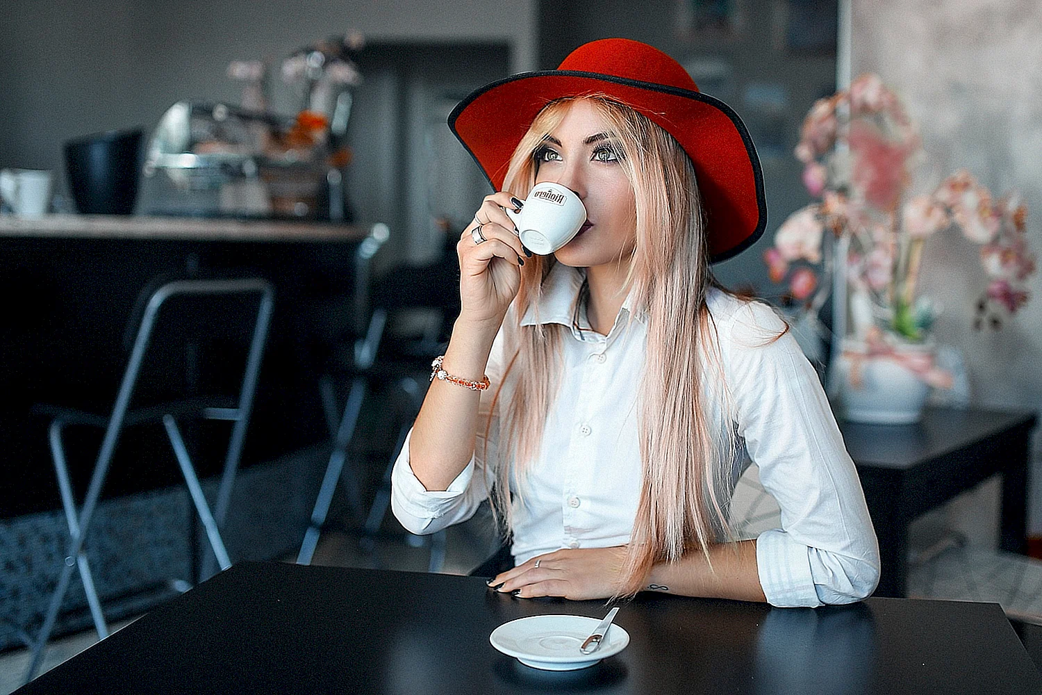 Девушка в шляпе пьет кофе