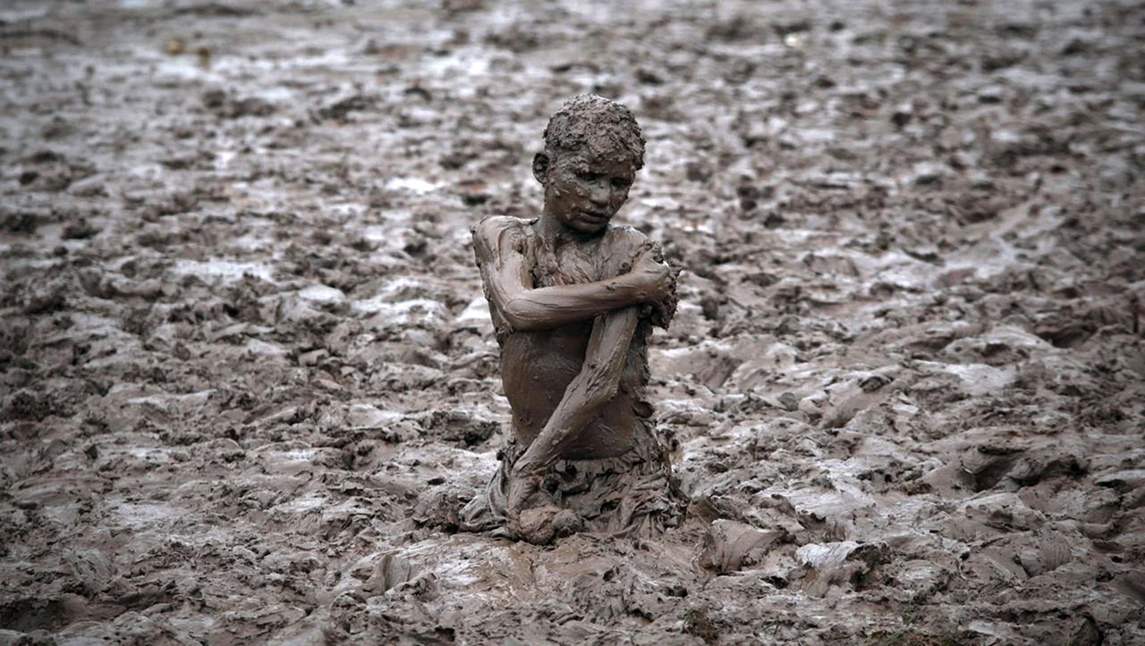Мальчик купается в грязи