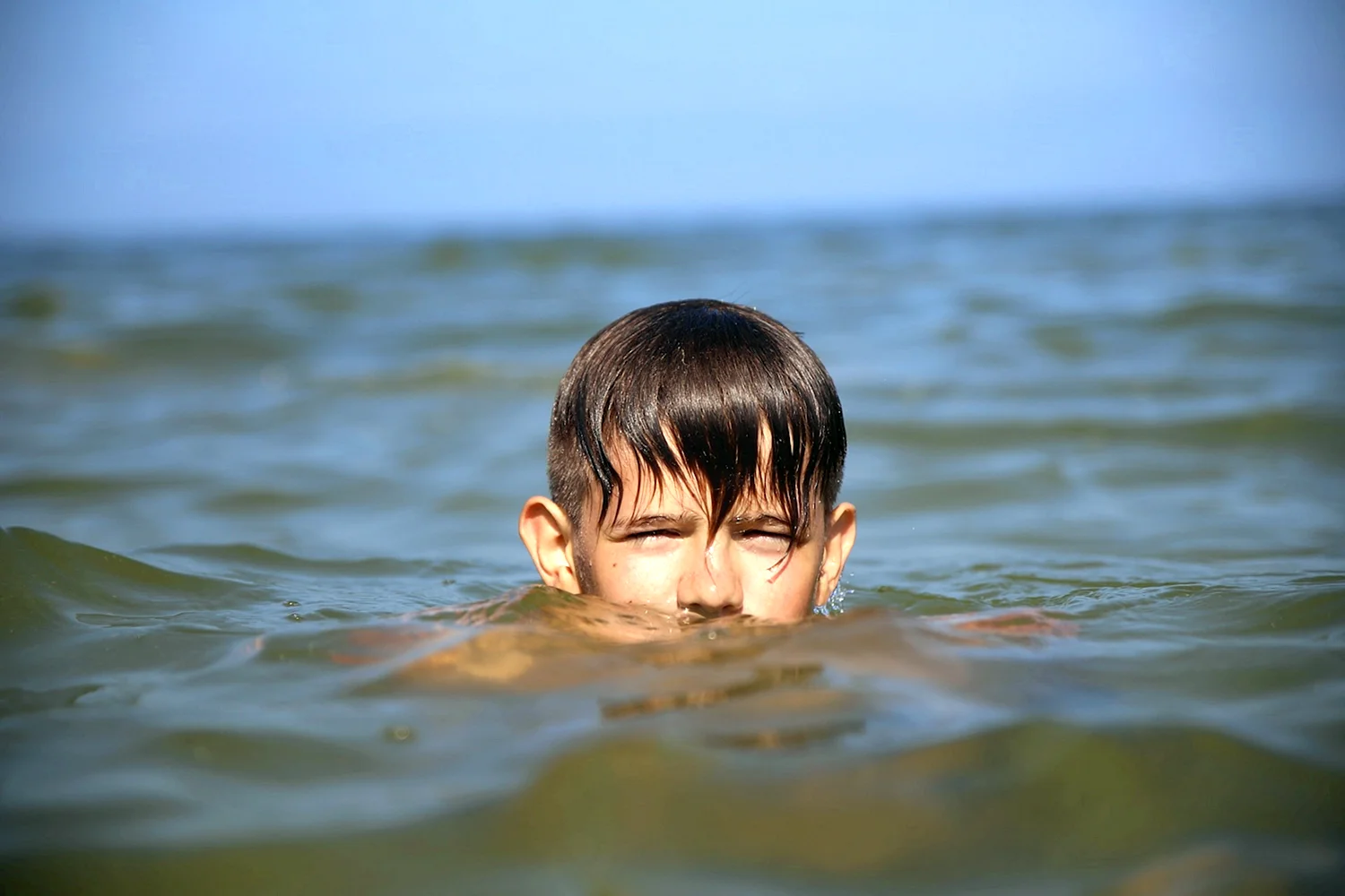 Мальчик купается в море