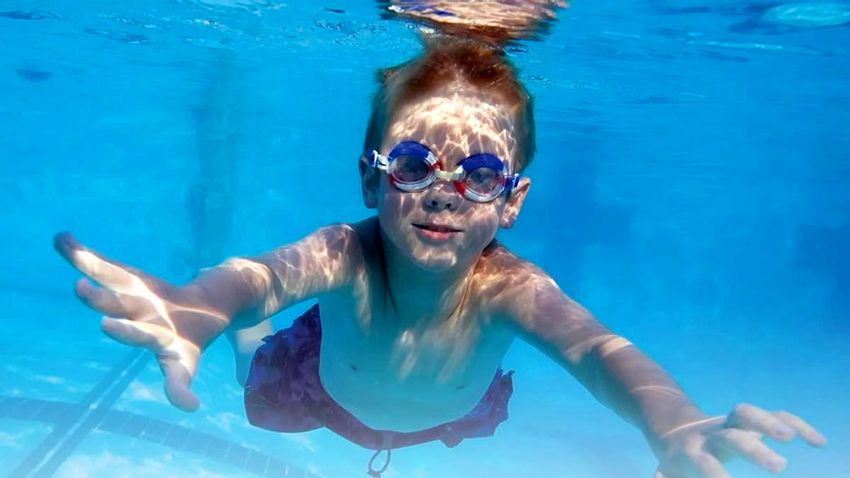 Мальчик под водой в бассейне