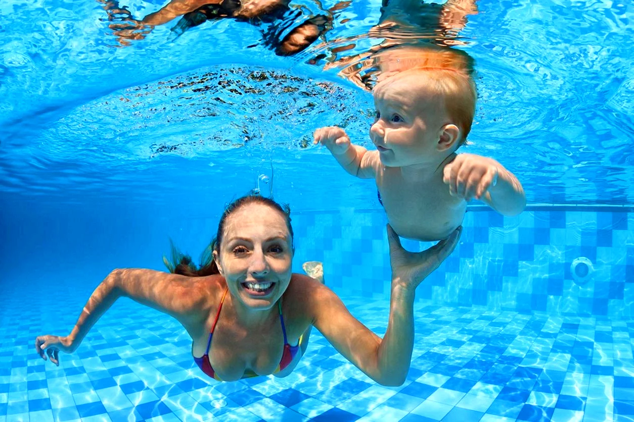 Родитель и ребенок ныряют в бассейне