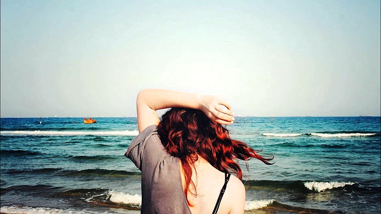 Рыжая девушка со спины на море