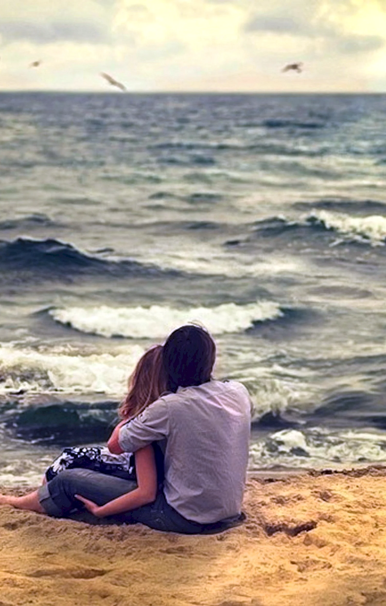 Парень с девушкой сидят на берегу моря